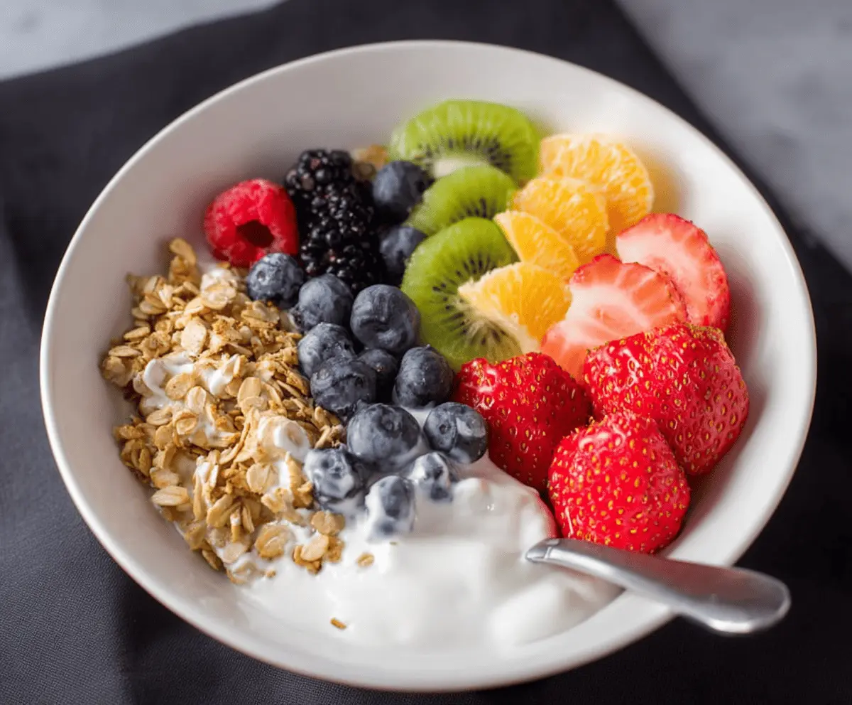 Colorful fruits and creamy yogurt breakfast bowl topped with fresh berries and sliced bananas.