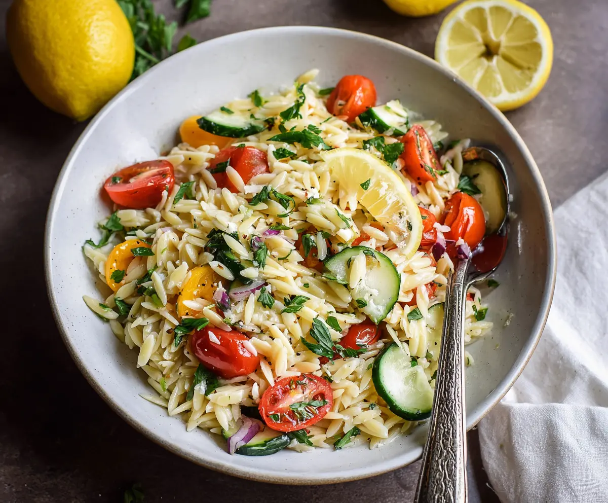 Fresh Lemon Orzo Pasta Salad with herbs and vegetables, served in a bowl for a light summer meal.