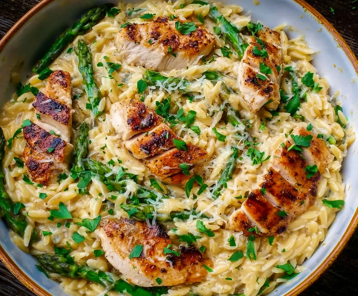 Delicious Parmesan orzo with tender chicken and fresh asparagus on a plate.