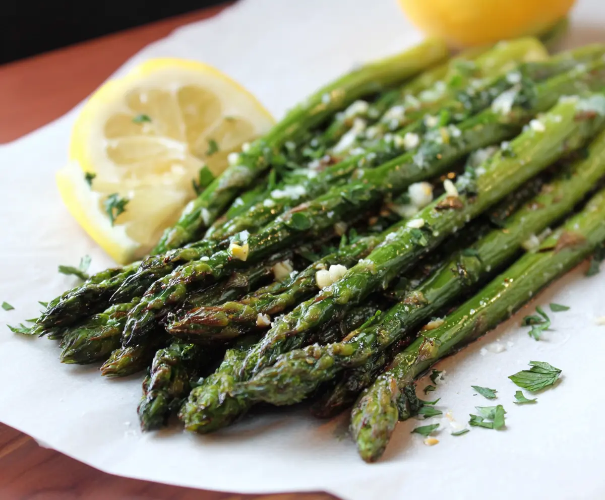 Delicious Garlic Herb Roasted Asparagus on a white plate, garnished with fresh herbs.