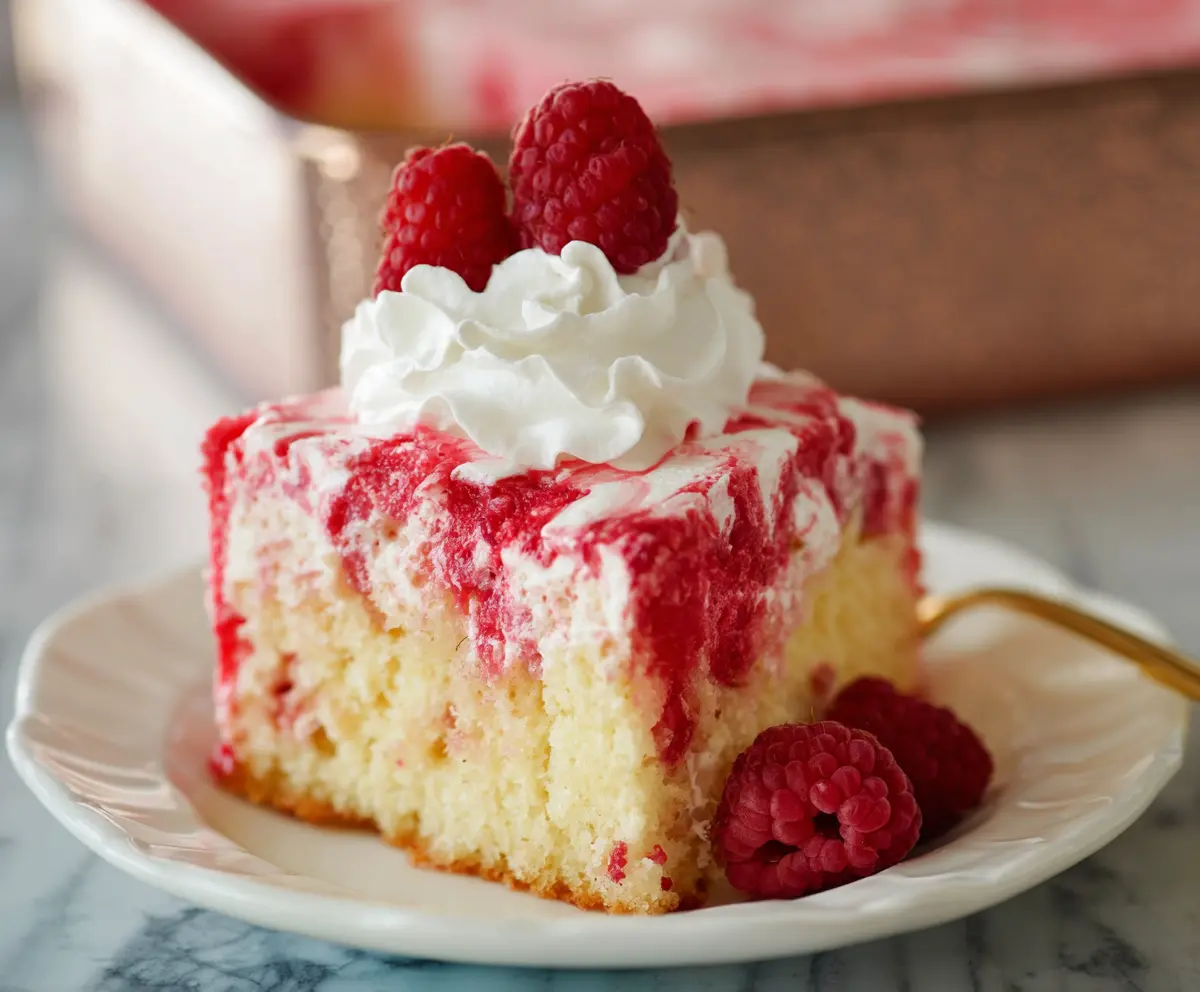 Delicious Raspberry Poke Cake with fresh raspberries and a moist, layered sponge dessert.